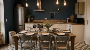 Een moderne keuken met een eettafel voor vier personen, een roestvrijstalen koelkast en een magnetron.