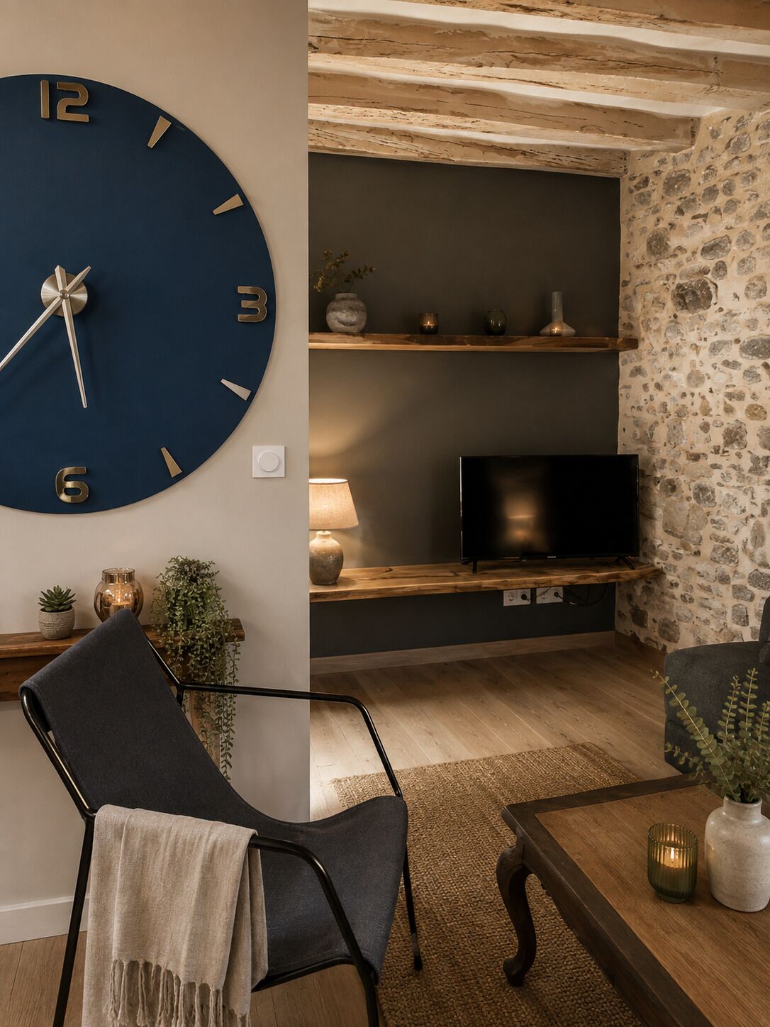 Un salon avec une grande horloge murale, un téléviseur à écran plat, un canapé et une table basse.