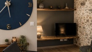 Een woonkamer met een grote wandklok, een flatscreen televisie, een bank en een salontafel.