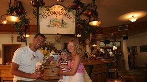 A family at a restaurant with a rustic interior, wooden furniture, and a sign reading "GEORGSHOF". - Georgshof (Podersdorf am See)