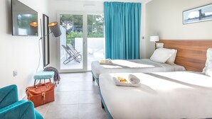 A hotel room with two beds, a TV, a desk, and a view of the outdoors.