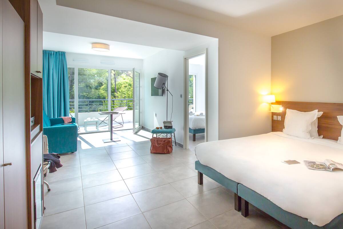 Habitación de hotel con una cama grande, un escritorio, una silla y vistas al exterior.