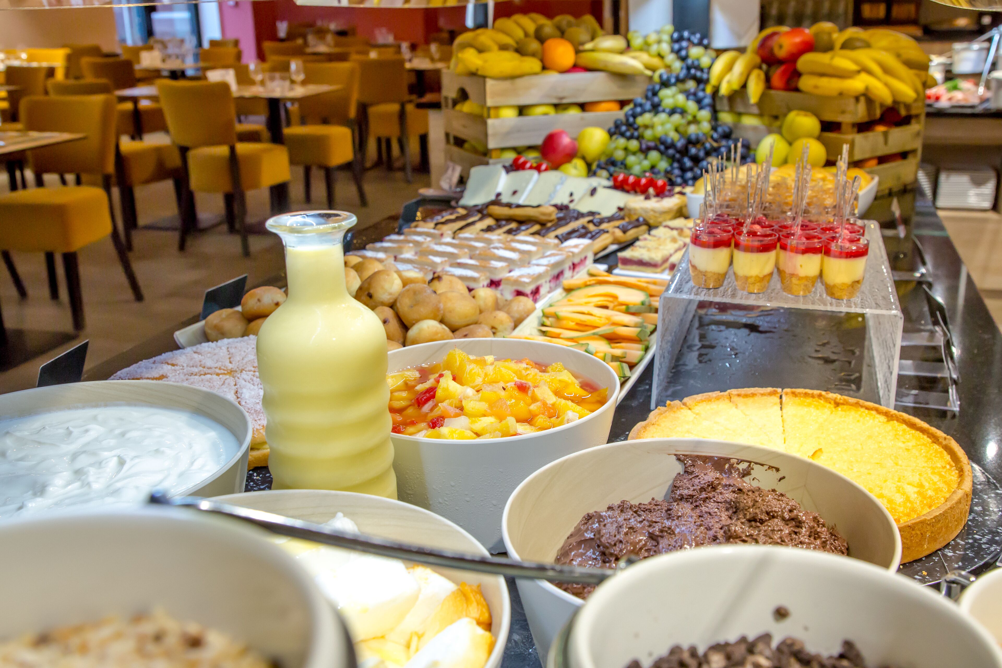 A buffet with various food items including fruits, desserts, and beverages.