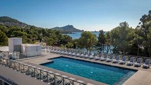 A pool with lounge chairs and a view of the sea and hills. - SOWELL HÔTELS La Plage (Saint-Raphael)