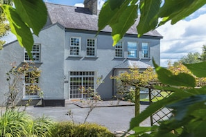 A two-story house with a grey exterior, large windows, and a front door. - Timoleague West Cork Priory House  (Cork)