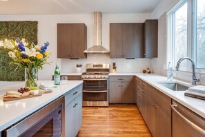 A modern kitchen with wooden cabinets, a stainless steel range, and a large window.