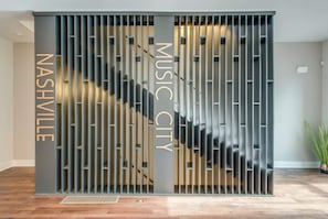 A modern interior with a metal partition featuring the words "NASHVILLE" and "MUSIC CITY" on it. - Fall in Nashville: ping pong game room, private balcony, sleeps 12 (Nashville)