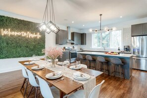 Una cocina moderna con una isla central, electrodomésticos de acero inoxidable y una pared verde.