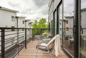 A balcony with a view of neighboring buildings, a table with chairs, and a vase with flowers. - Fall in Nashville: ping pong game room, private balcony, sleeps 12 (Nashville)