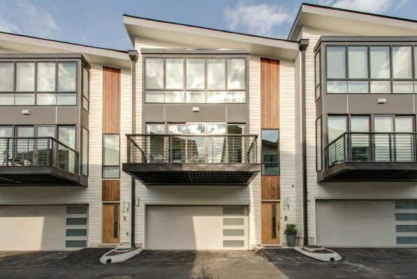 Un edificio residencial moderno de varios pisos con ventanas grandes, balcones y un garaje.