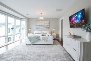 Un dormitorio moderno con una cama grande, un televisor de pantalla plana y vistas al exterior.