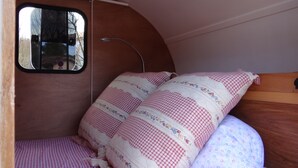 Een knus slaapgedeelte met een geruit bedovertrek en een raam.