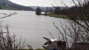 Uitzicht op een meer met een caravan en een stoel aan het water.