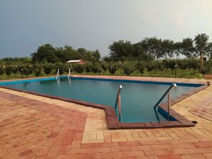 A rectangular swimming pool with a blue interior, surrounded by a brick deck.