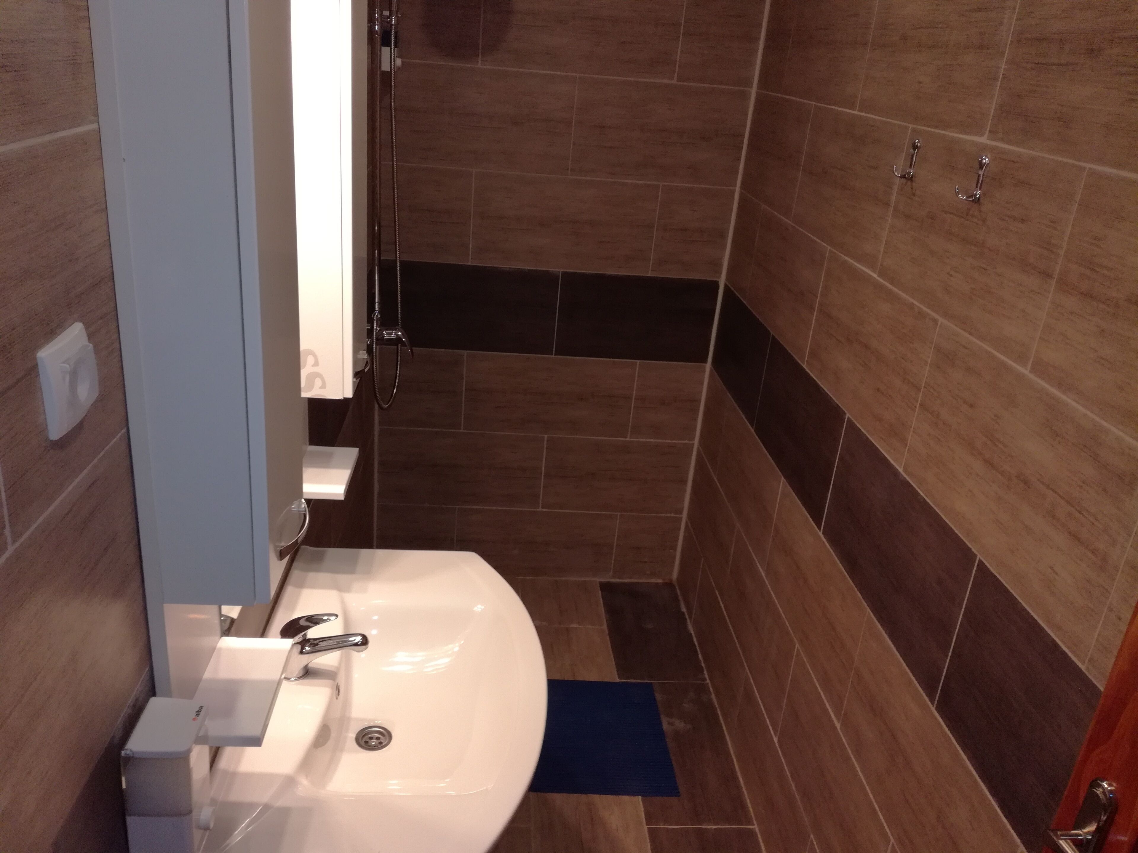 A bathroom with a white sink, a shower, and a toilet.