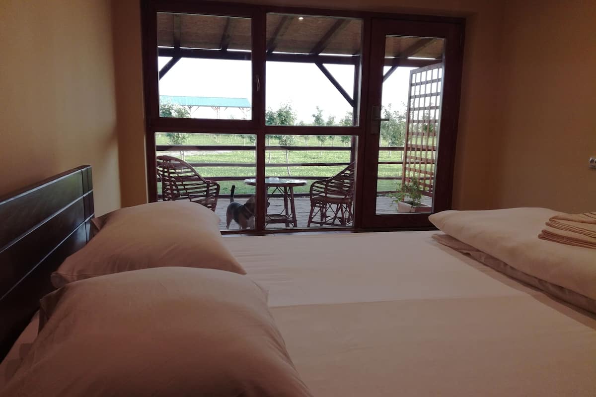 A room with two beds, a large sliding glass door leading to an outdoor patio with chairs and a table.