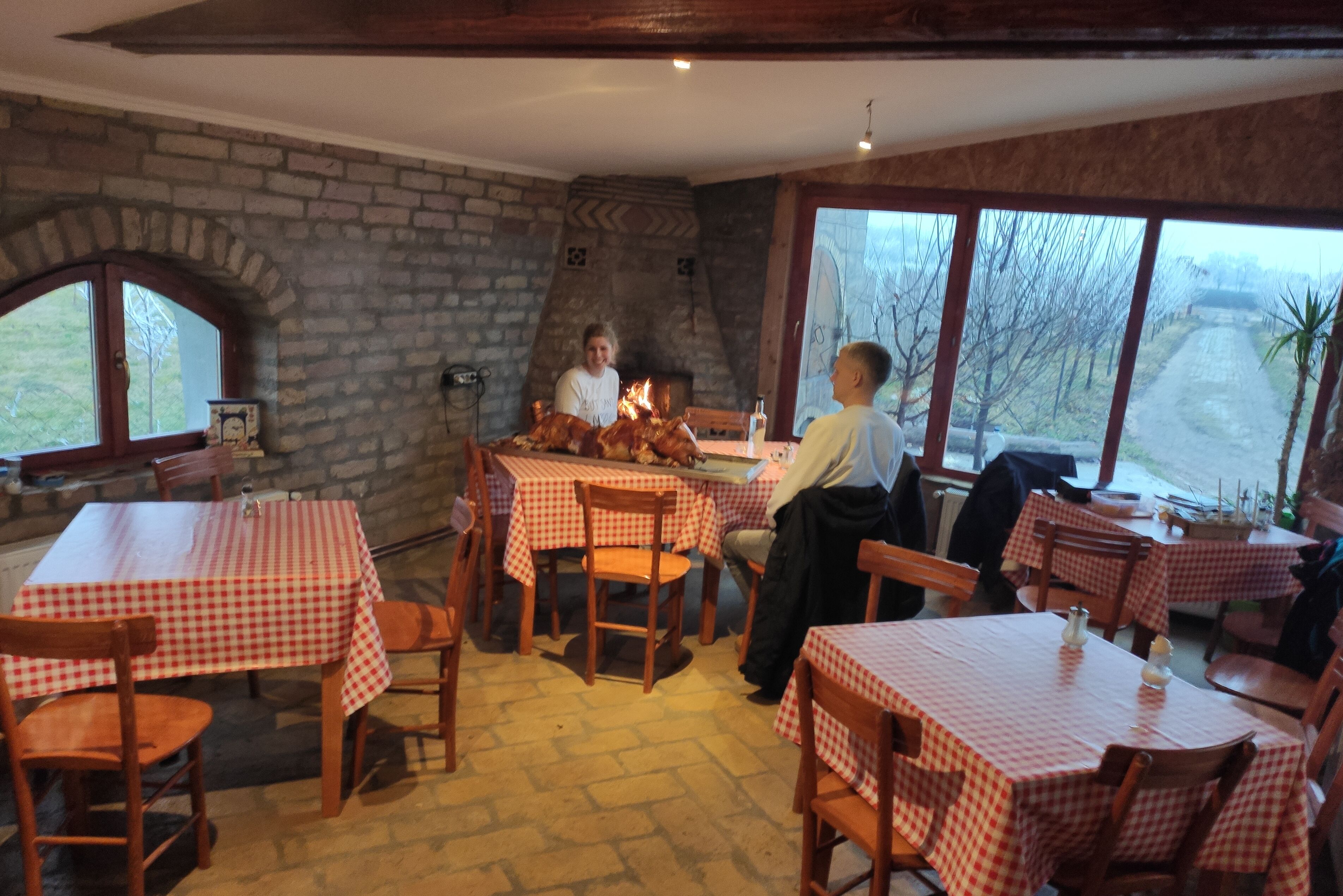 Ein Restaurant mit karierten Tischdecken, Steinwänden und einem Kamin aus Backsteinen.