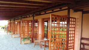A covered outdoor seating area with wooden partitions, potted plants, and metal bowls on the floor. - Salas Farma 47 (Novi Sad)
