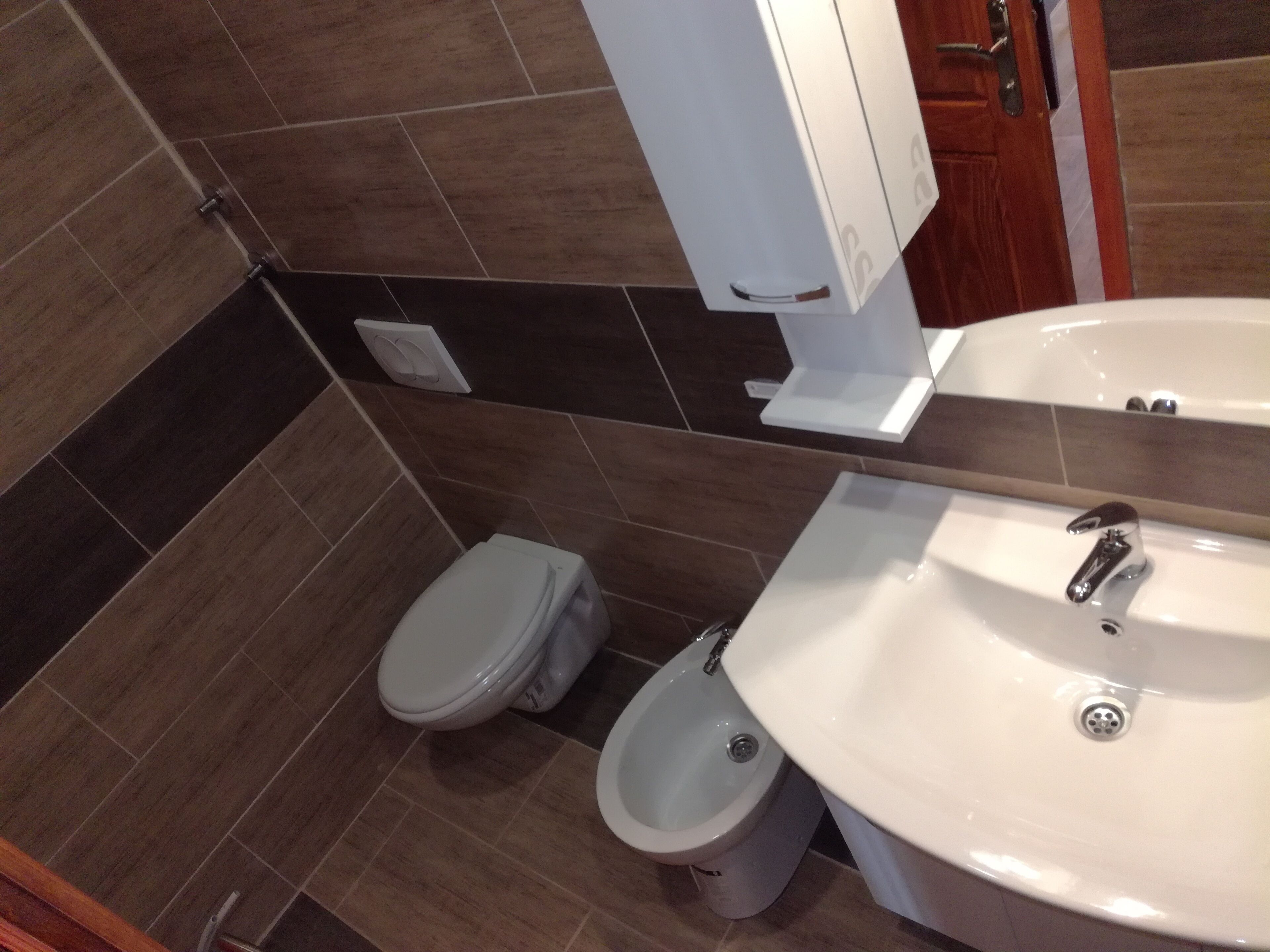 A bathroom with a toilet, bidet, and sink.