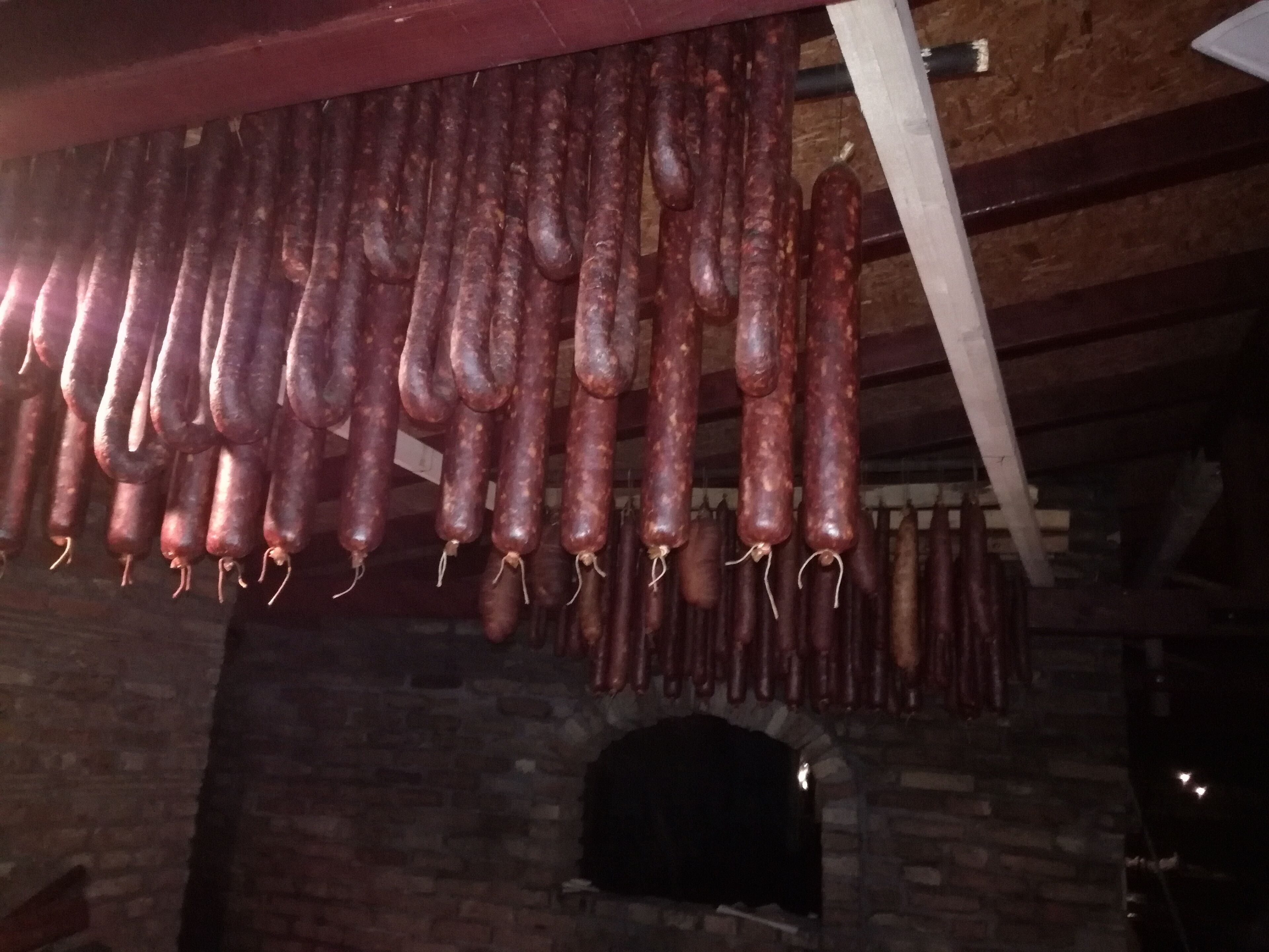 Una hilera de salchichas colgando de una viga en un edificio de ladrillo rústico.