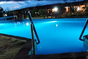 A swimming pool with metal railings and a paved deck area.