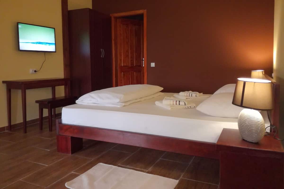A hotel room with a bed, a desk, a television, and a lamp.