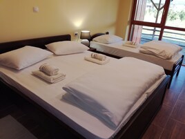Habitación de hotel con tres camas, cada una con toallas y almohadas ordenadas.