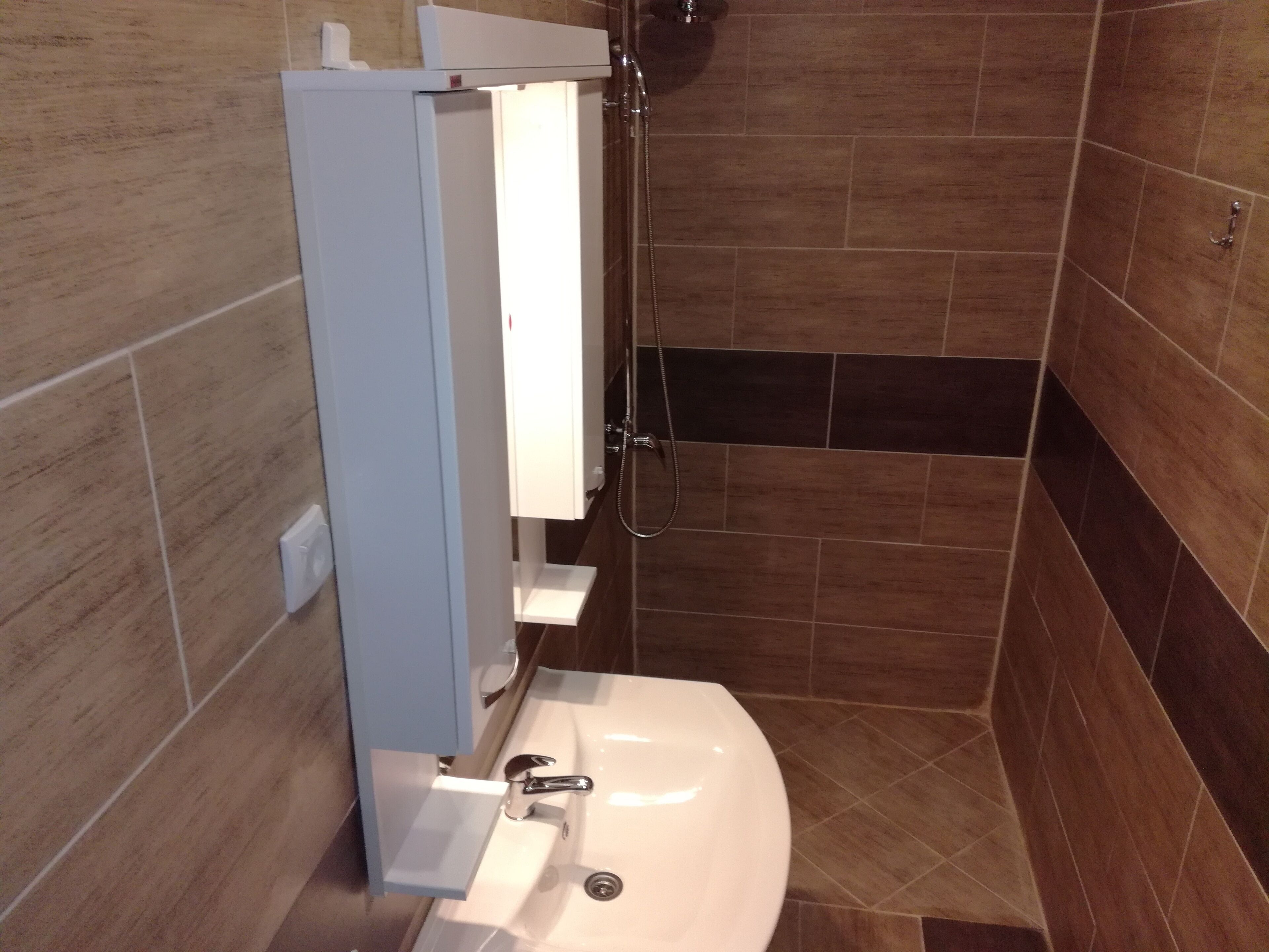 A bathroom with a white sink, a shower, and a mirror.