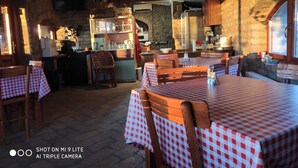 A cozy restaurant with checkered tablecloths, wooden chairs, and stone walls. - Salas Farma 47 (Novi Sad)