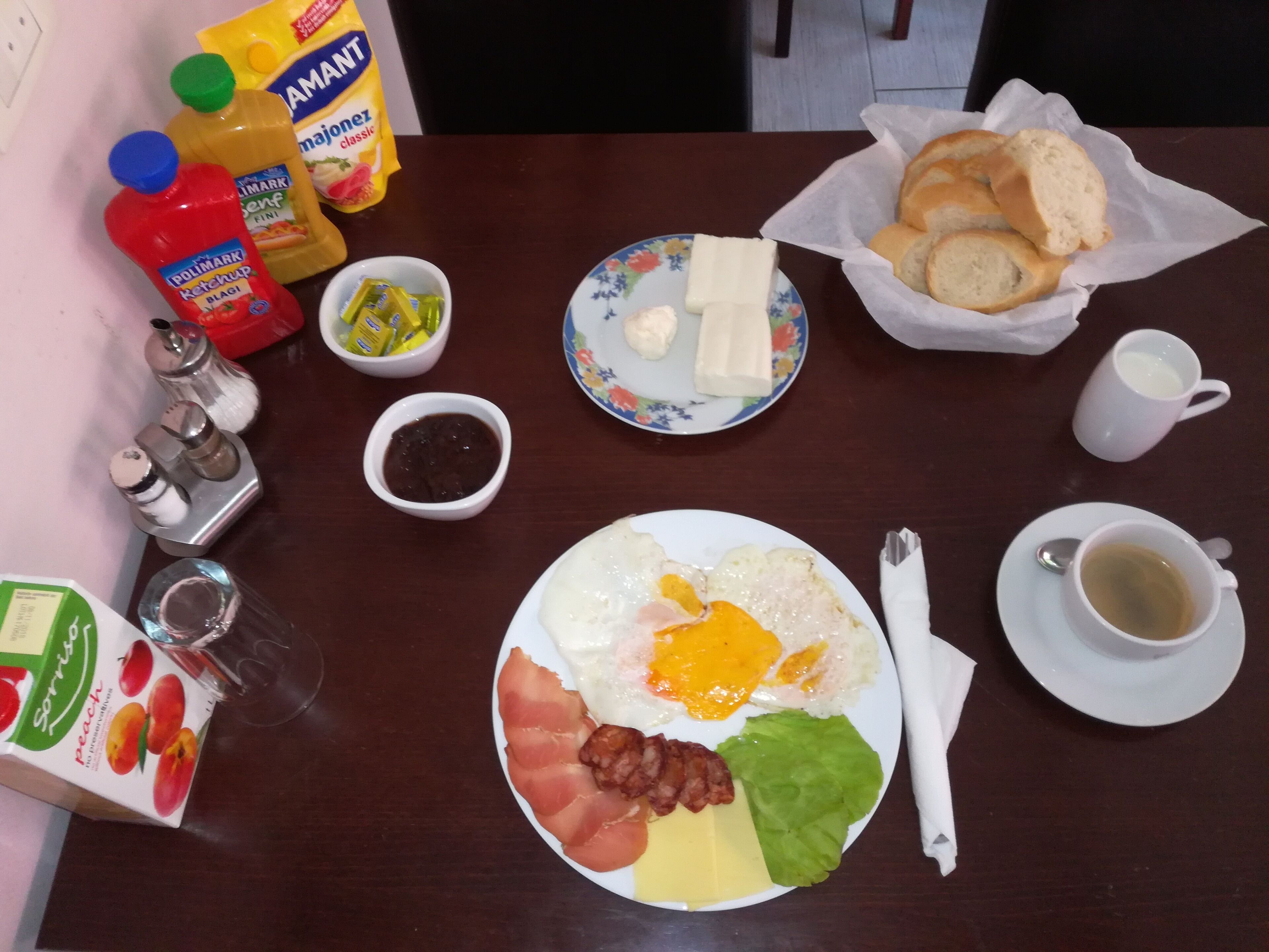 A breakfast table with various food items, condiments, and a cup of tea.