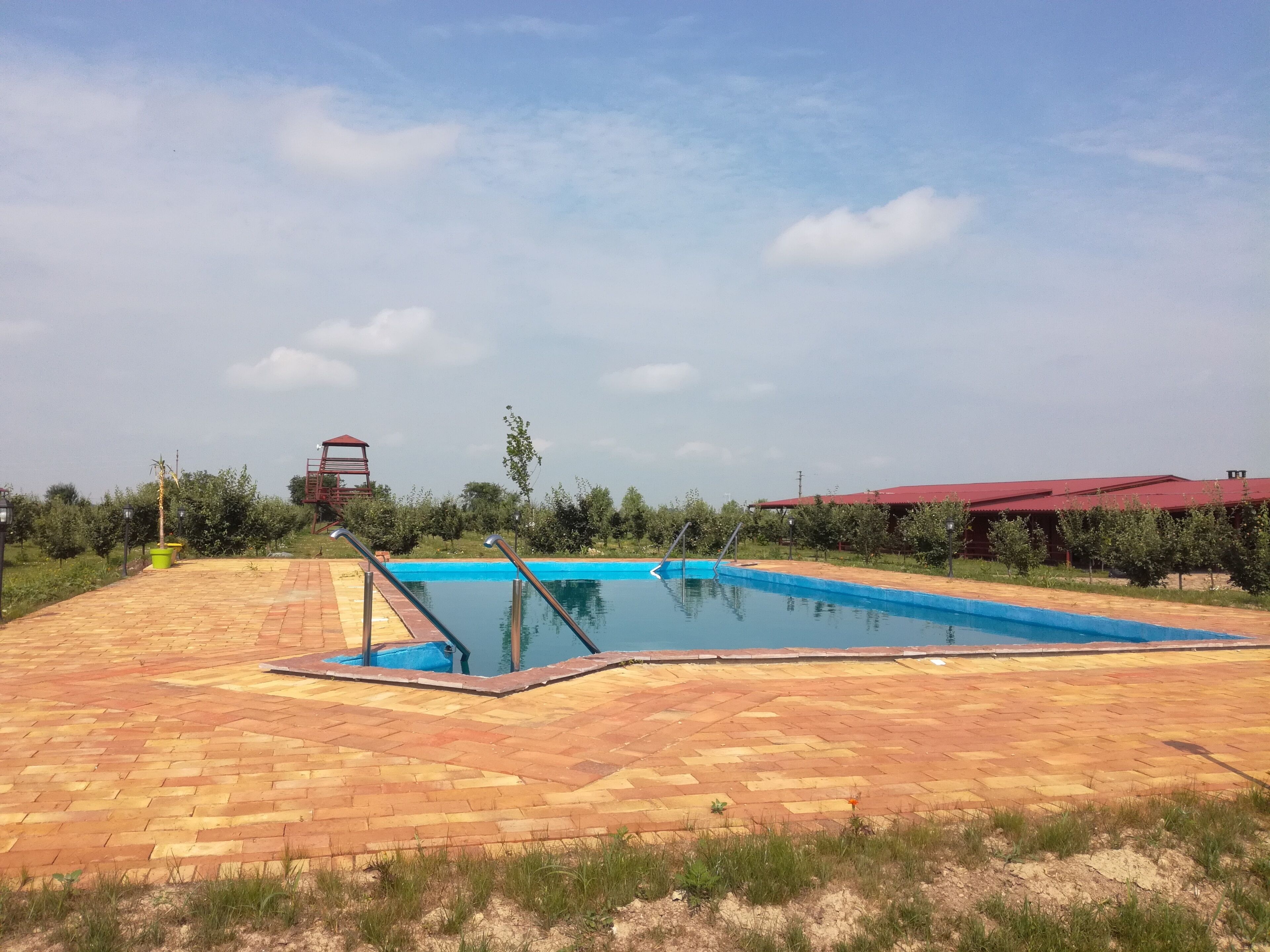 Una piscina con un edificio de techo rojo al fondo.