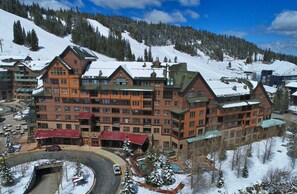 A multi-story hotel with a ski slope in the background.