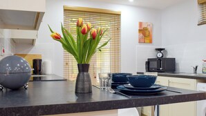 Een moderne keuken met een zwart aanrecht, een vaas met tulpen en een magnetron.