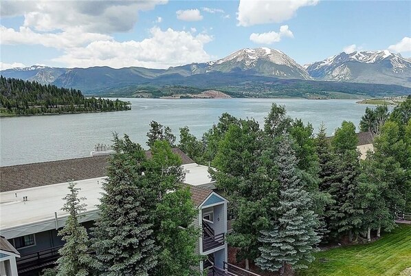 A lakeside view with mountains in the background, a dock, and a small building with a staircase.
