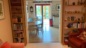 Un salon chaleureux avec un coin repas, une bibliothèque et un canapé rouge.