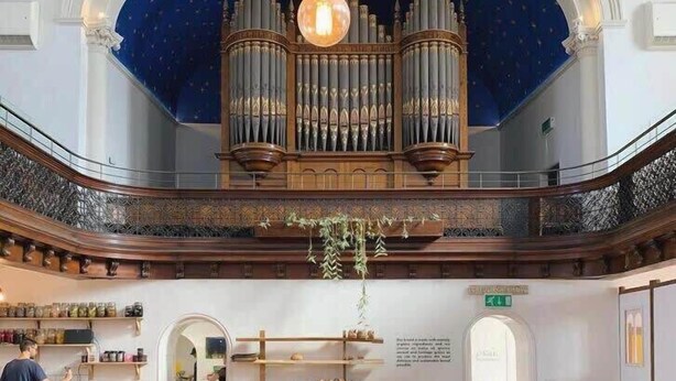 Un restaurant avec un plafond haut, un orgue central et une mezzanine.