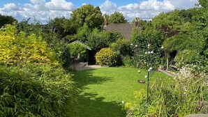 Un jardin luxuriant, avec une grande variété de plantes et une petite construction en arrière-plan.