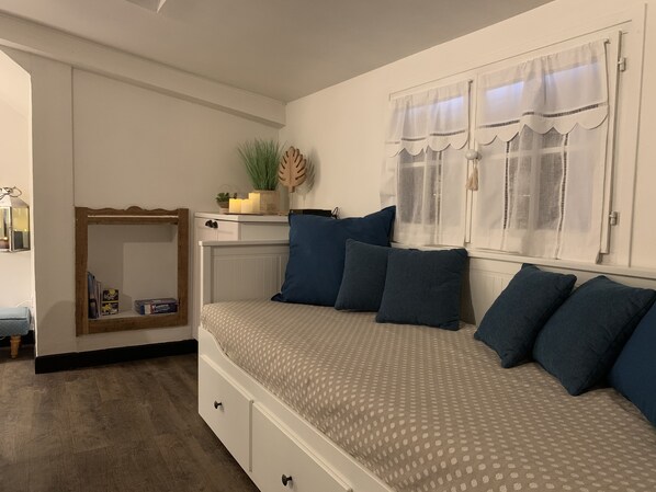 Un dormitorio con cama, cómoda, espejo y ventana con cortinas.