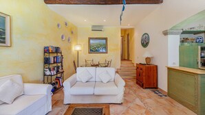 A living room with a white sofa, a bookshelf, a painting, and a staircase leading to another room.
