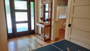 Ein Zimmer mit einem Tischtennis-Tisch, einem Spiegel und einer Tür mit satinierten Glasscheiben.