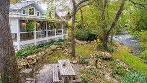 Ein Haus mit einer Veranda, einem Kiesweg und einem Fluss.