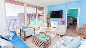 Un salón amplio con balcón, televisión de pantalla plana y vista al mar.
