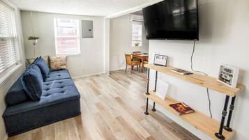 A modern living room with a sofa, a TV mounted on the wall, a wooden table with a Wi-Fi sign, and a bench.