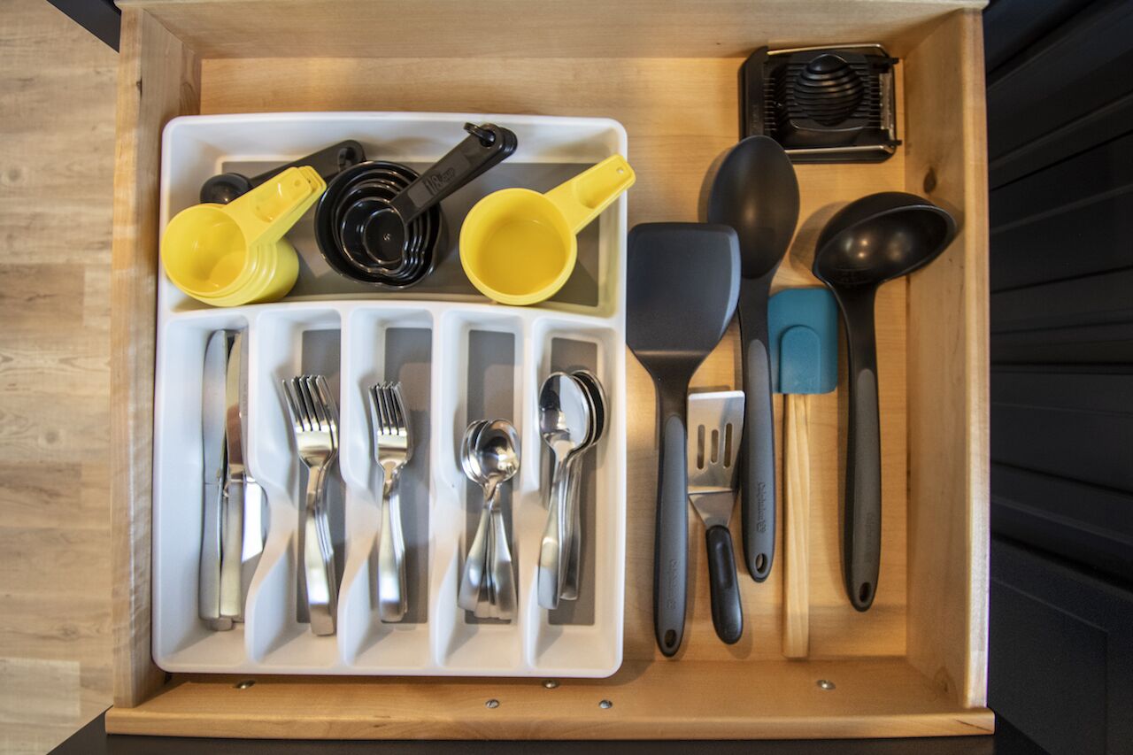 A drawer with utensils and kitchen tools organized in compartments.