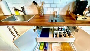 A kitchen with a stainless steel sink, wooden countertop, and a drawer organizer with utensils and kitchen items. - 203-Remodeled Studio Downtown San Jose, CA (San Jose)