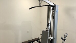 A home gym with a bench press, a squat rack, and a cable machine. - 203-Remodeled Studio Downtown San Jose, CA (San Jose)