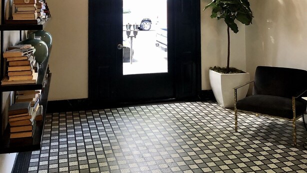 A hallway with a black door, a potted plant, a bookshelf, and a tiled floor. - 203-Remodeled Studio Downtown San Jose, CA (San Jose)