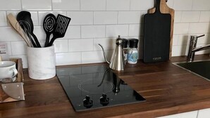 Una cocina con encimera de madera, estufa empotrada y armarios blancos.