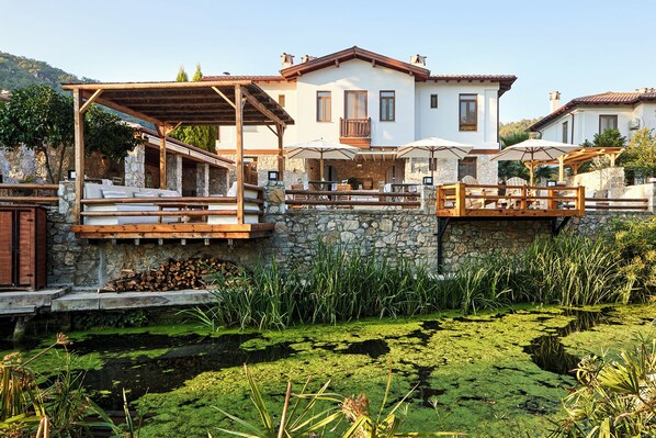 Eine Villa mit Außenbereich, Steinmauern und einem Teich.