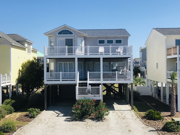 A two-story house with a balcony, a small garden, and a clear sky.